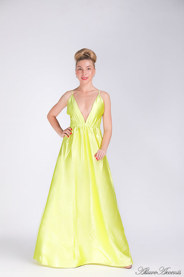 Woman wearing a lemon colored long satin dress that has a deep v neckline.