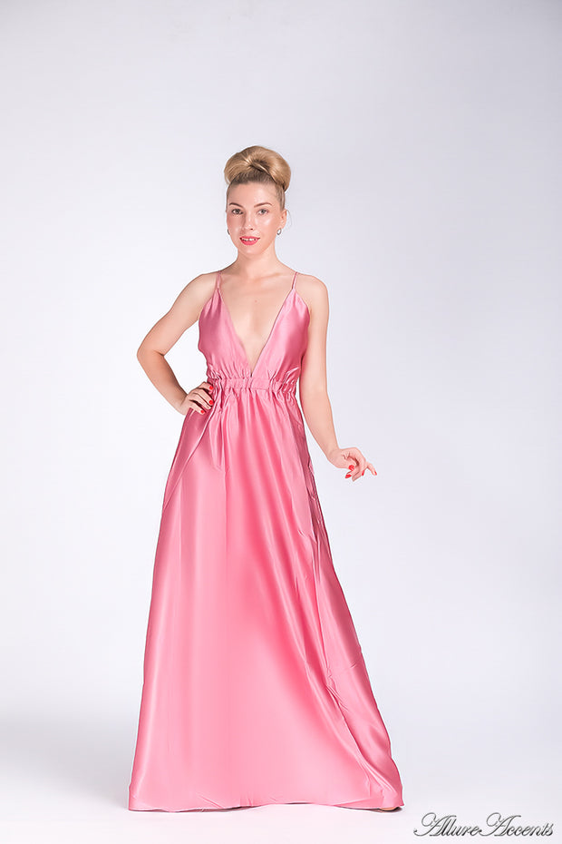 Woman wearing a pink long satin dress that has a deep v neckline.