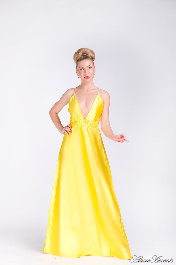 Woman wearing a yellow long satin dress that has a deep v neckline.