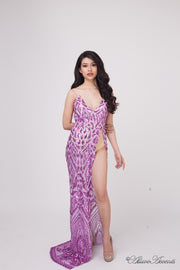 Woman wearing a long purple sequined dress with a high slit. 