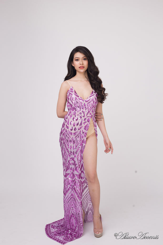 Woman wearing a long purple sequined dress with a high slit. 