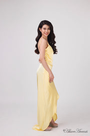 Woman wearing a long yellow colored silk dress with ruching.