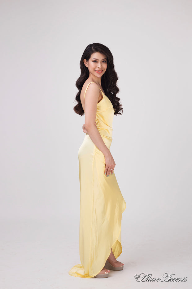 Woman wearing a long yellow colored silk dress with ruching.