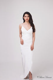 Woman wearing a long white colored silk dress with ruching.