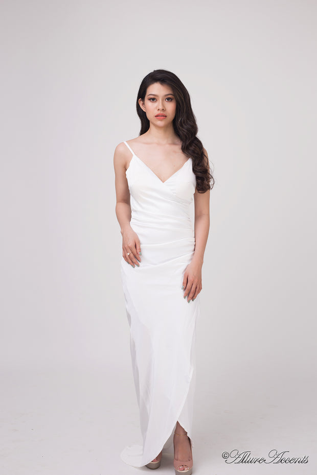 Woman wearing a long white colored silk dress with ruching.