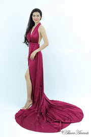 Woman wearing a dark red/maroon silk satin, halter neck gown with a high leg slit.