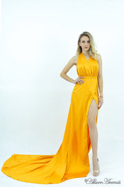 Woman wearing a yellow silk satin, halter neck gown with a high leg slit.