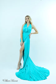 Woman wearing a tiffany blue silk satin, halter neck gown with a high leg slit.