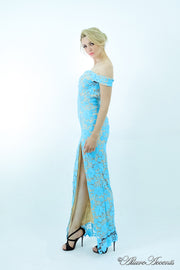 Woman wearing a baby blue off-the-shoulder lace dress with a front slit.