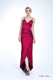 Woman wearing a long wine red colored silk dress with ruching.